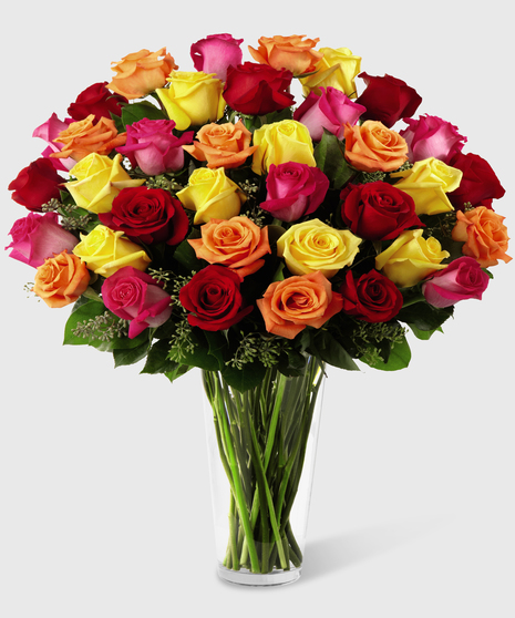 Pink, orange, red and yellow roses in a clear glass vase.