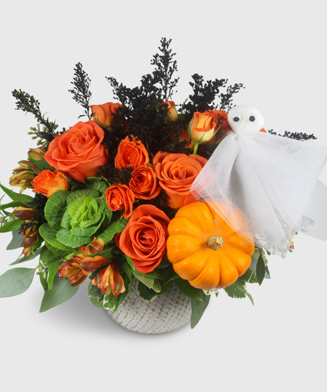 A halloween bouquet of orange flowers featuring a mini pumpkin and ghost